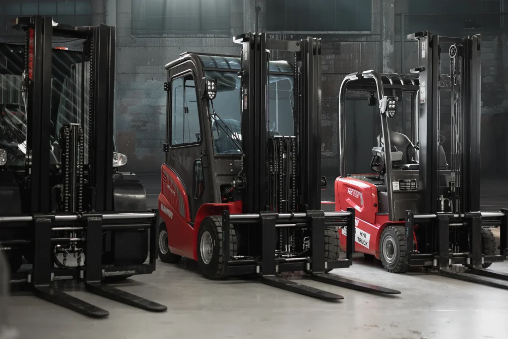 Tre röda Håkanssons Truck-gaffeltruckar står parkerade inomhus på ett betonggolv i en lager- eller industrimiljö.